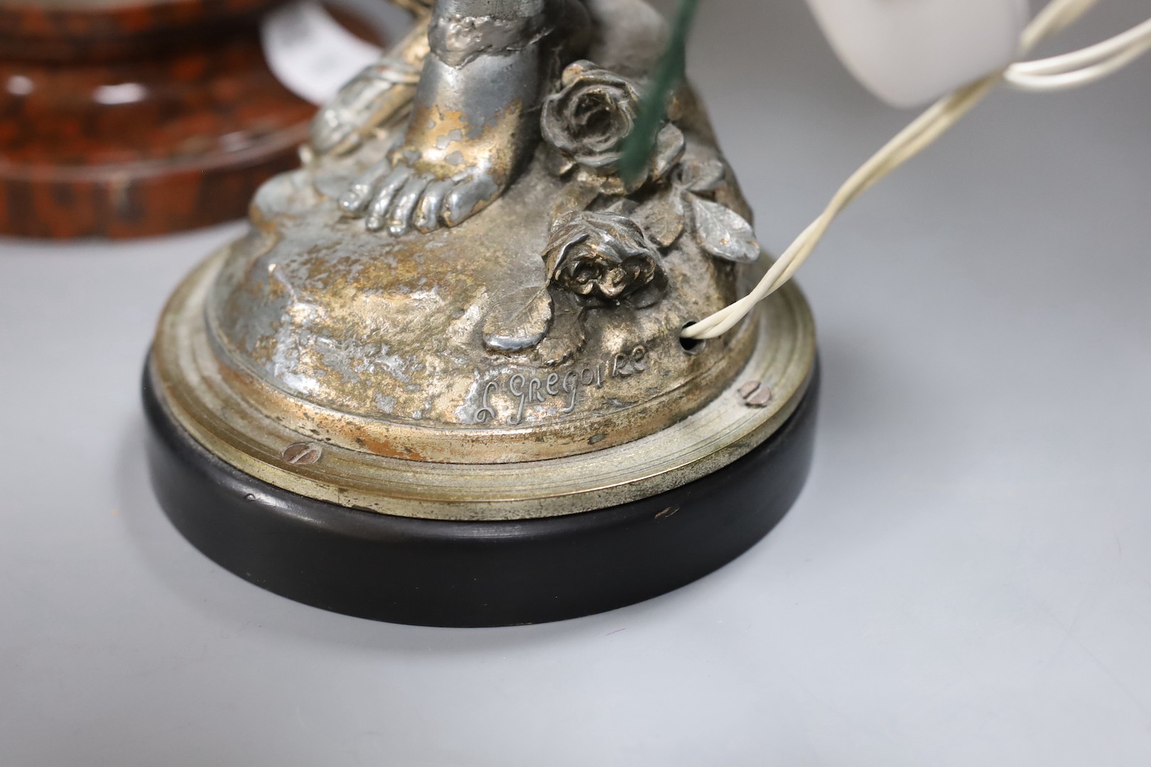 A pair of silvered metal cherub lamps in dancing pose bearing torch lamp, signed L. Gregoire